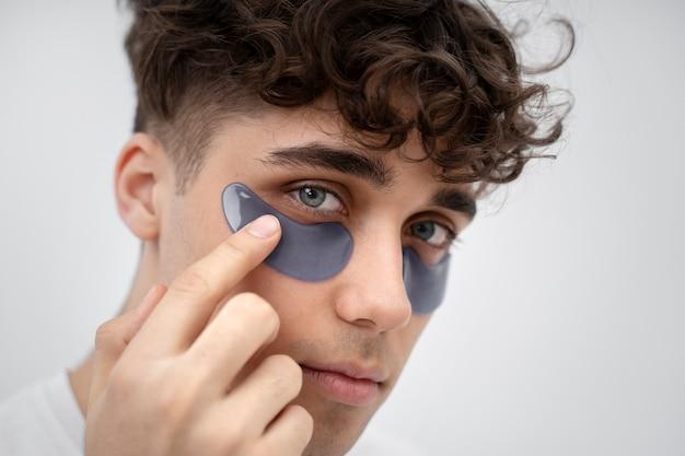 Man applying under-eye patches for skincare routine