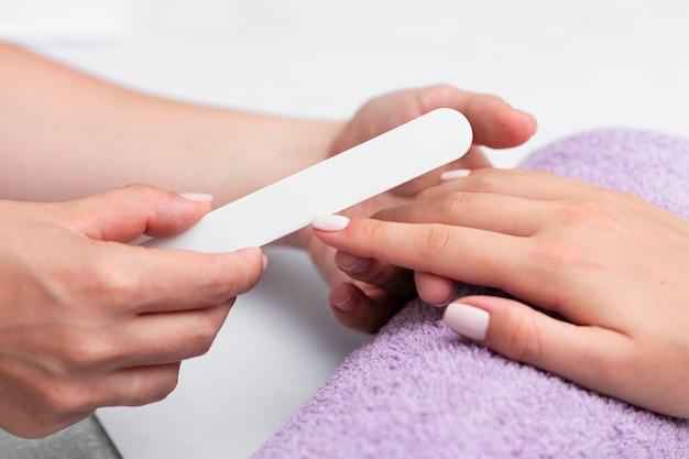 Manicurist filing client's nails during a manicure session