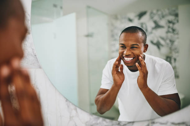 Man smiling while applying facial cream in mirror