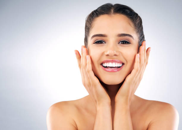 Portrait of a joyful young woman with healthy skin smiling and touching her face